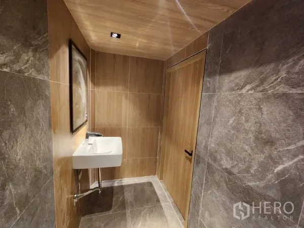 零售空间 出租在Pathum Wan, Bangkok - 卫生间带木质饰面与岩石纹瓷砖，壁挂式洗手盆。