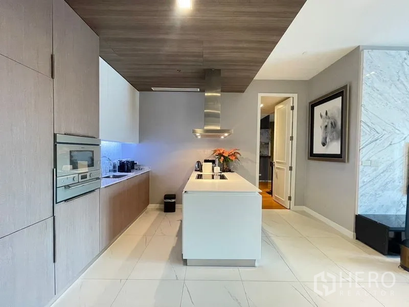 Condominium for rent in Pathum Wan, Bangkok - Sleek kitchen showing island cooktop, hood and built-in oven cabinetry.