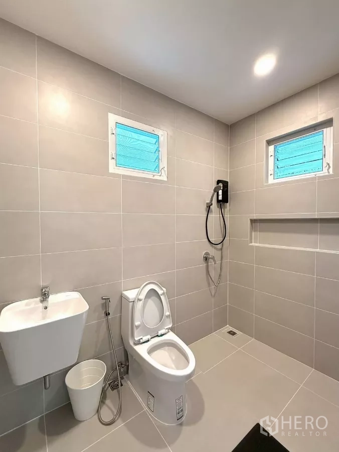 Detached House for rent in Bang Phli, Samut Prakan - Spacious bathroom with gray tiles, toilet and handheld shower.