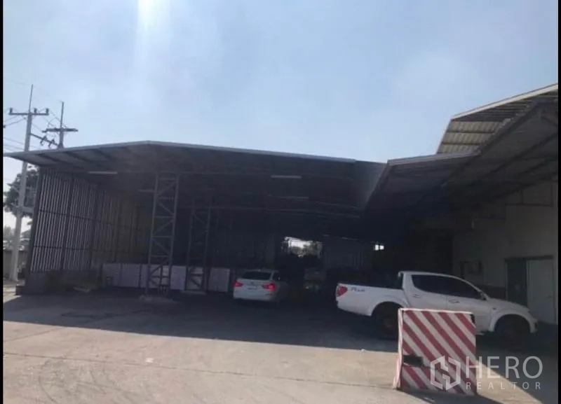 Factory for rent in Bang Khla, Chachoengsao - Covered loading dock with vehicles and a wide driveway for trucks.