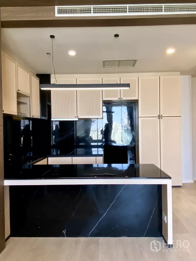 คอนโด ขายในPathum Wan, Bangkok - มุมมองด้านหน้าครัว แสดงไอส์แลนด์หินอ่อนสีดำ ตู้สูงบิวท์อิน และเครื่องใช้ครบ