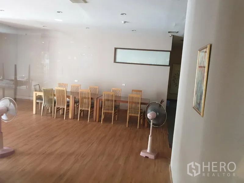 零售空间 出租在Khlong Toei, Bangkok - 开放式就餐区，长条木桌、木椅与电风扇，木地板。