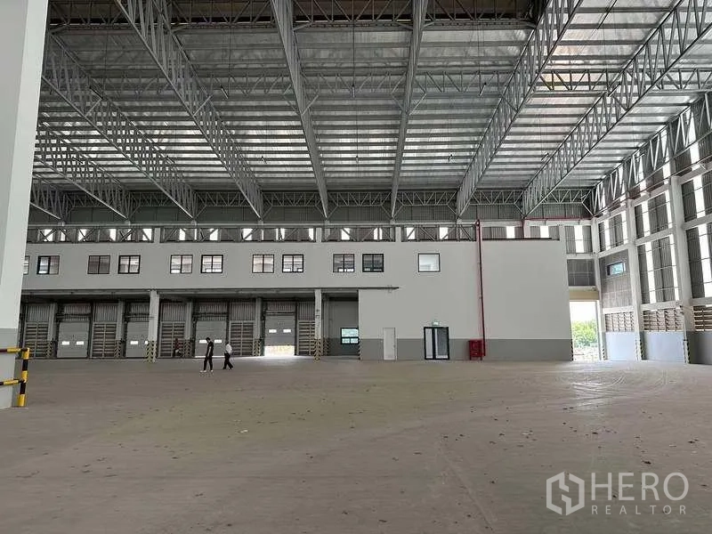 工厂 出租或出售在Samut Prakan - 宽阔厂房大厅，高挑空间与多组装卸门及夹层办公区。
