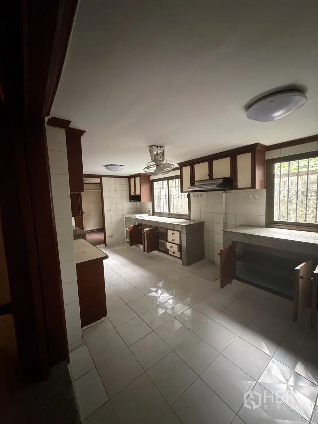 Home Office for rent in Watthana, Bangkok - Spacious tiled kitchen with wooden cabinetry, range hood, and barred windows.