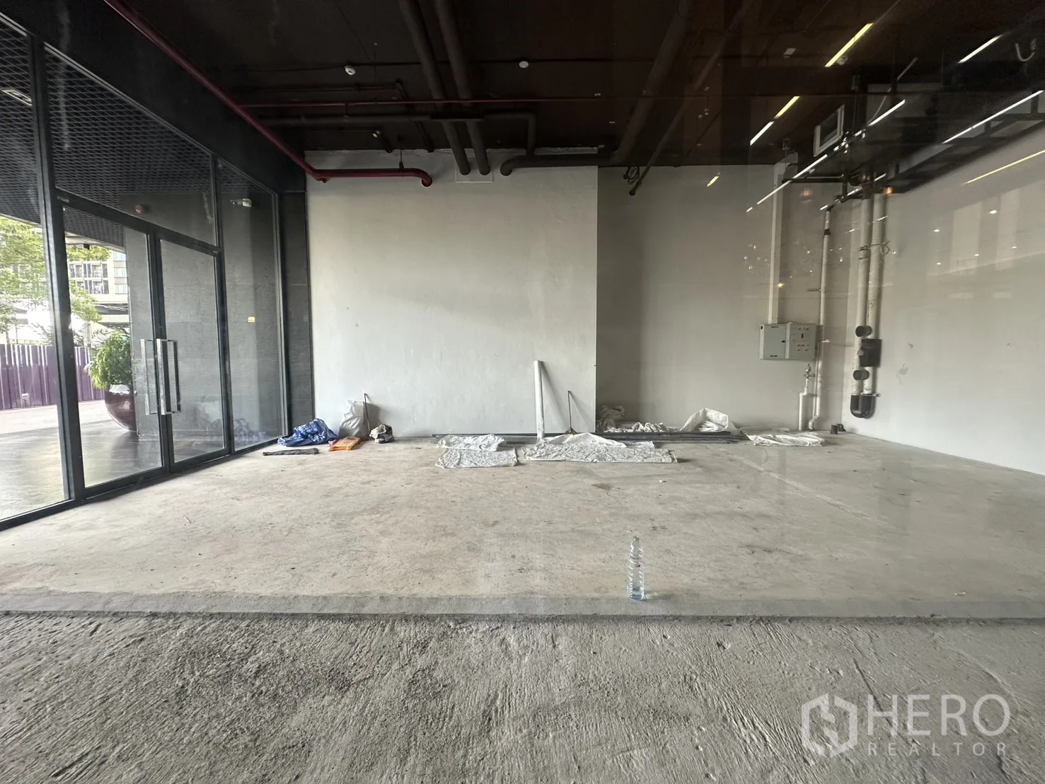 Retail Space for rent in Khlong Toei, Bangkok - Open-plan interior with concrete floors, white walls, and visible utility lines.