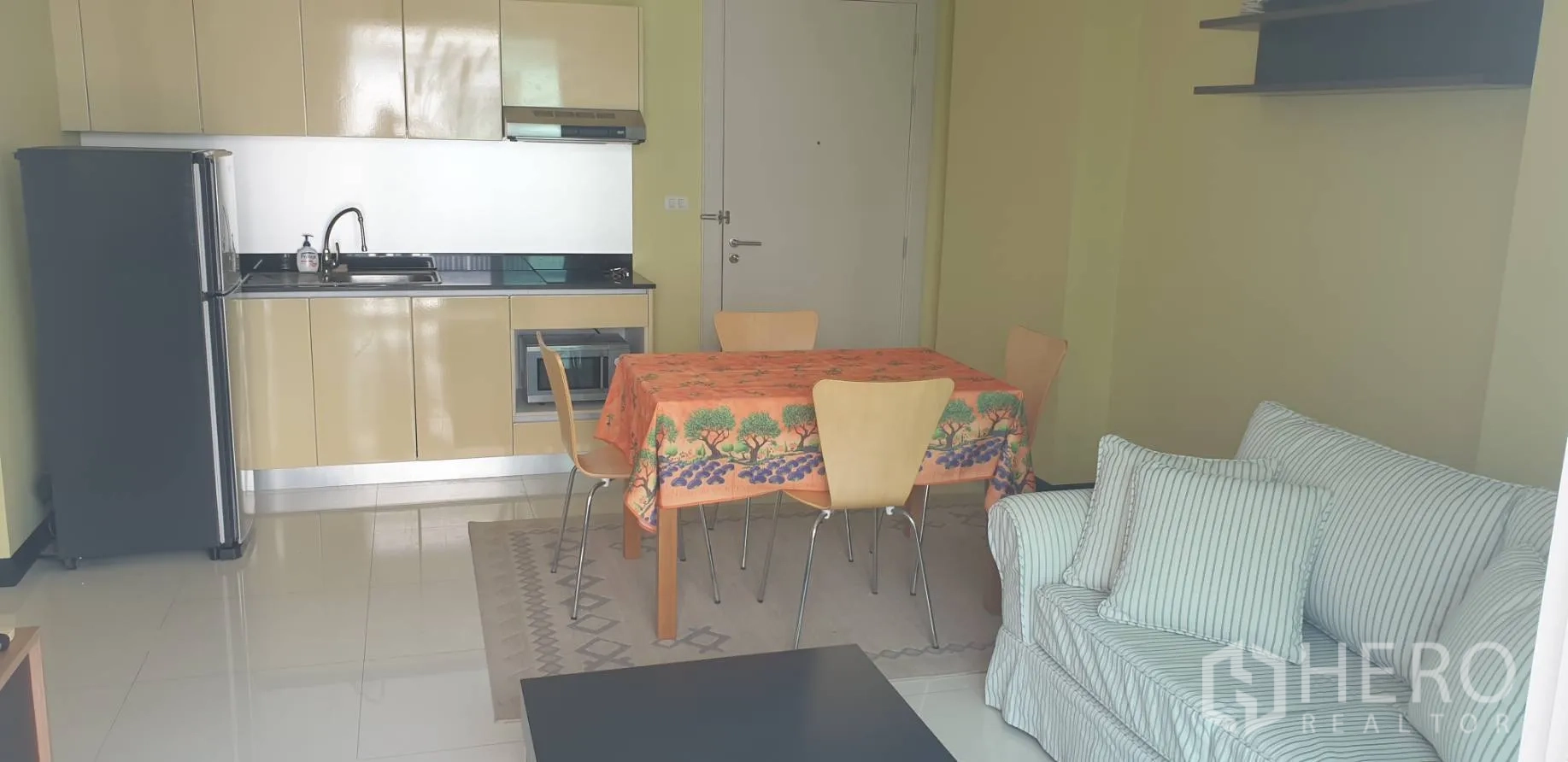 คอนโด ให้เช่าในKhlong Toei, Bangkok - ครัวบิลต์อินสีเบจพร้อมไมโครเวฟ ชุดโต๊ะทานข้าว 4 ที่นั่ง และโซฟาลายทาง