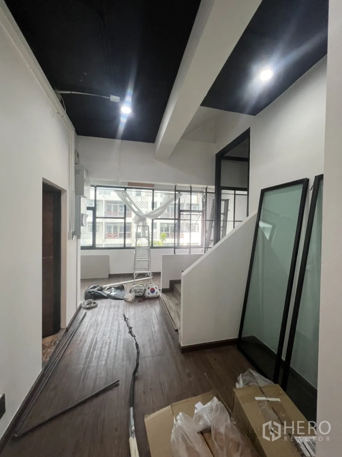 Retail Space for rent in Watthana, Bangkok - Upper-floor corridor under renovation with black ceiling, big windows and scattered materials.