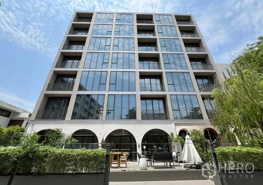 零售空间 出租在Watthana, Bangkok - 当代中高层外观，整面落地窗与一层拱形开口，下方是景观露台。