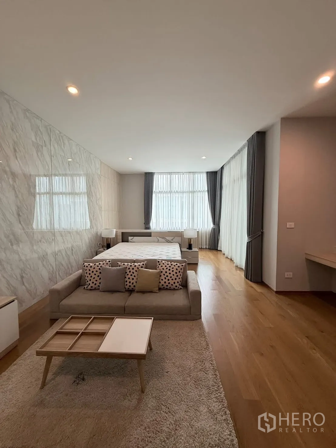 Townhouse for rent in Saphan Sung, Bangkok - Master suite with sofa, bed, large windows and marble feature wall.