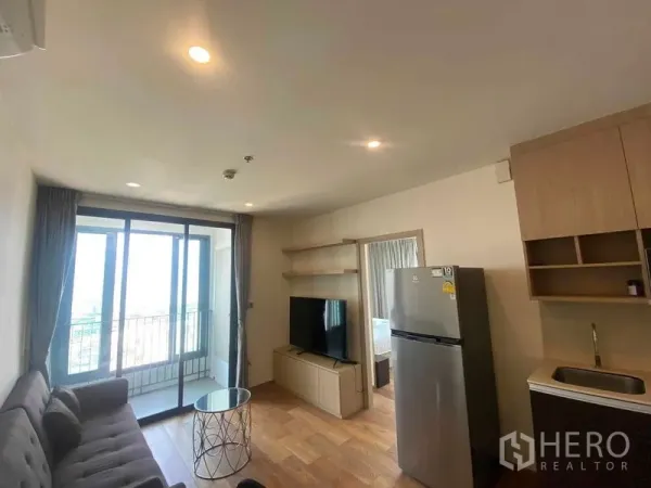 Condominium for rent or sale in Ratchathewi, Bangkok - Bright living room with sofa, TV cabinet and sliding doors to the balcony.