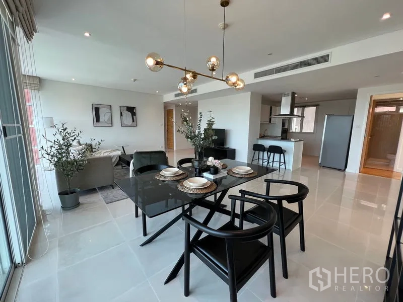 Condominium for rent in Watthana, Bangkok - Dining space with black table and pendant lights beside the open kitchen.