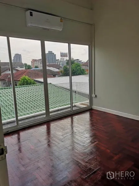 联排别墅 出租或出售在Din Daeng, Bangkok - 卧室设大推拉门连阳台，空调，俯瞰社区屋顶景观。