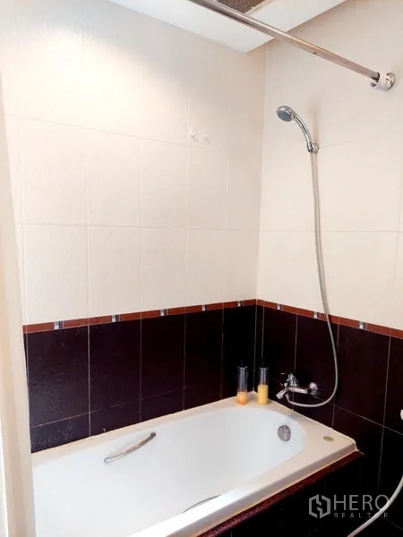 อพาร์ทเมนท์ ให้เช่า - ภาพระยะใกล้อ่างอาบน้ำพร้อมฝักบัวและผนังกระเบื้องครึ่งผนัง
