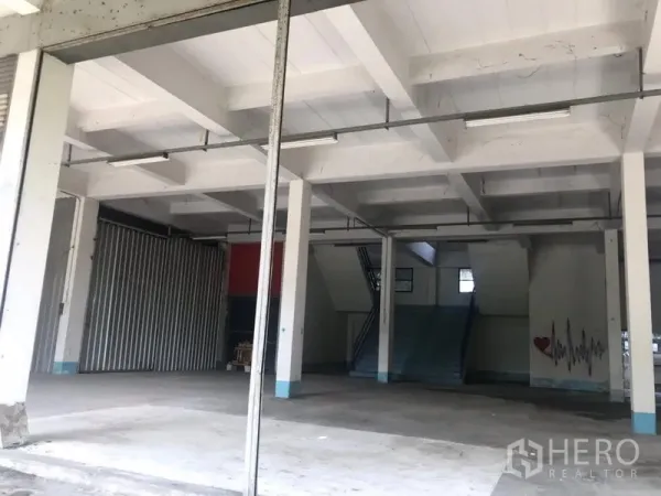 货栈 出租在Bueng Kum, Bangkok - 仓库内部，高挑空间，混凝土地面与立柱，楼梯通往夹层，设有日光灯照明。