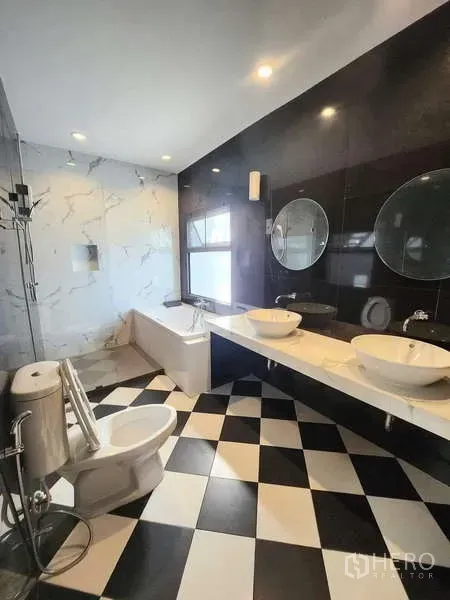 联排别墅 出租在Watthana, Bangkok - 宽敞卫浴，浴缸、双台盆与黑白棋盘格地面。