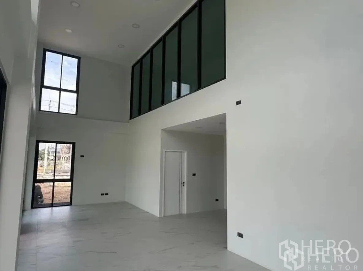 โกดัง for sale in Lam Luk Ka, Pathum Thani - โถงต้อนรับเพดานสูงสองชั้น ผนังสีขาว พื้นกระเบื้อง และช่องกระจกชั้นลอย