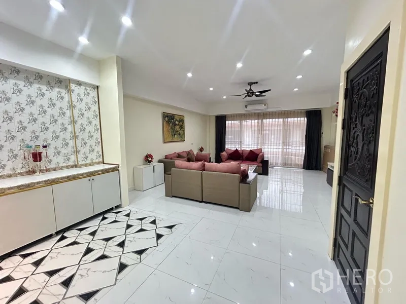 สำนักงานที่บ้าน ให้เช่า - ห้องนั่งเล่นสว่าง ชุดโซฟาสีชมพู พื้นลายกระเบื้องดีไซน์ และตู้บิวท์อินกับผ้าม่านสูง