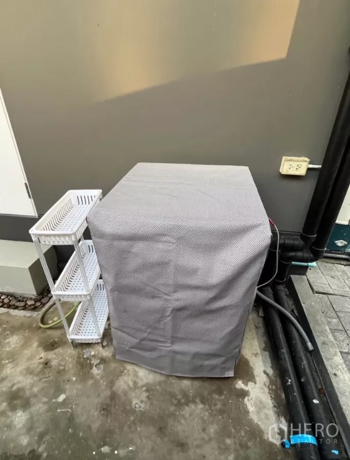 Detached House for rent in Prawet, Bangkok - Outdoor utility corner with a covered washing machine and storage shelves.