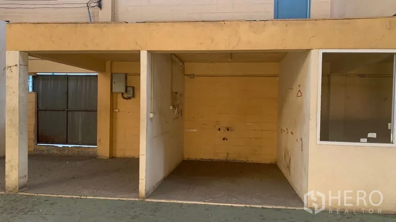 Warehouse for rent in Mueang Nakhon Pathom, Nakhon Pathom - Covered utility alcove with pillars, meter box, and an adjacent metal gate.