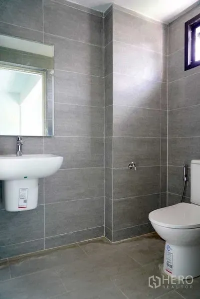 Office Space for sale in Khan Na Yao, Bangkok - Modern restroom with grey tiled walls, wall-mounted sink, and toilet.