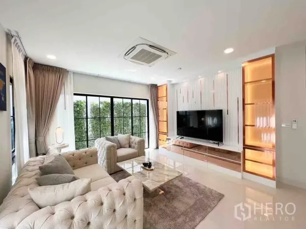 Detached House for rent or sale in Saphan Sung, Bangkok - Bright living room with tufted sofas, large TV wall and floor-to-ceiling windows