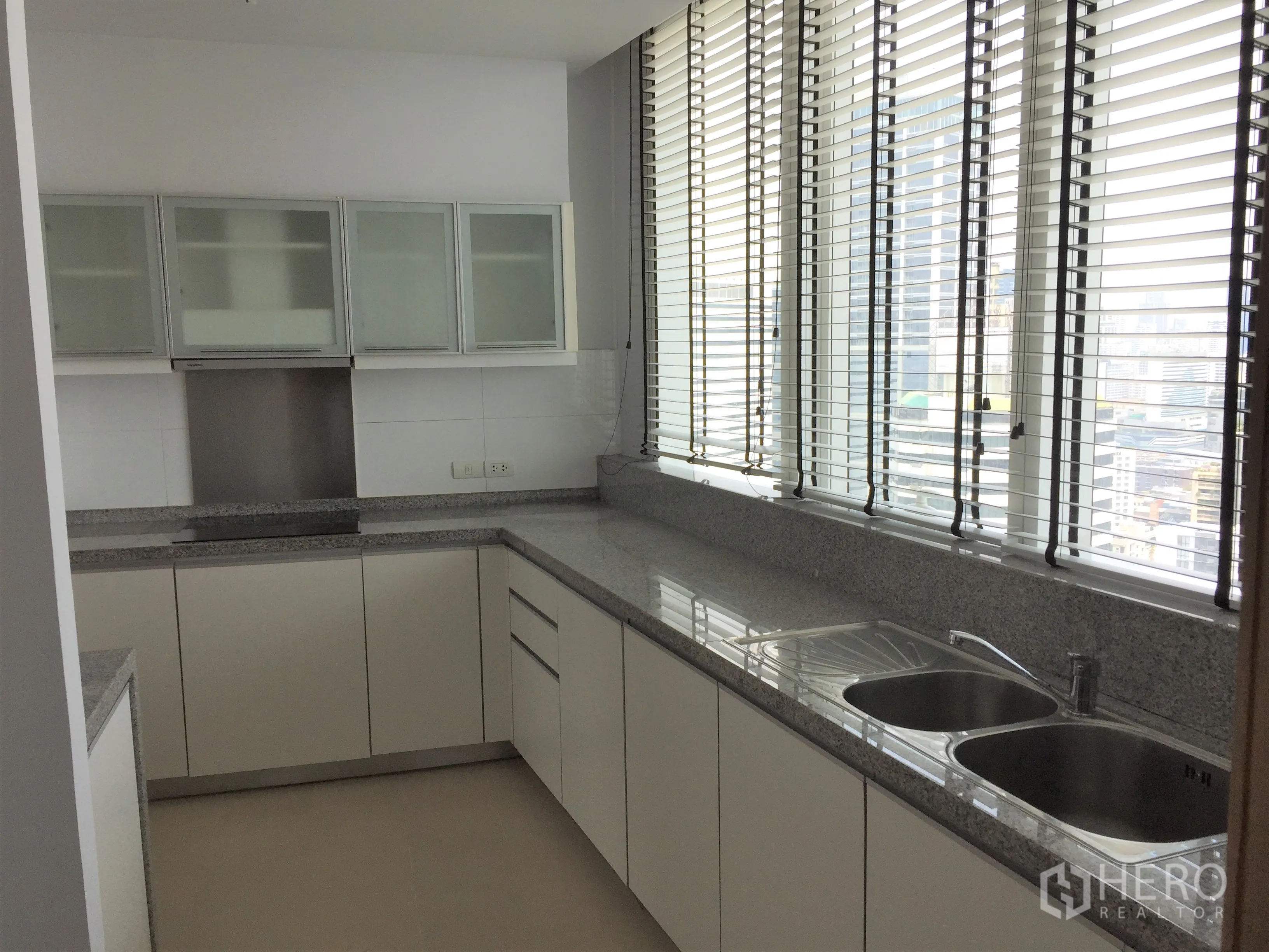 คอนโด ให้เช่าในKhlong Toei, Bangkok - ครัวรูปตัว U พร้อมอ่างล้างจานคู่ เคาน์เตอร์หินแกรนิตยาว และบานเกล็ดหน้าต่าง.