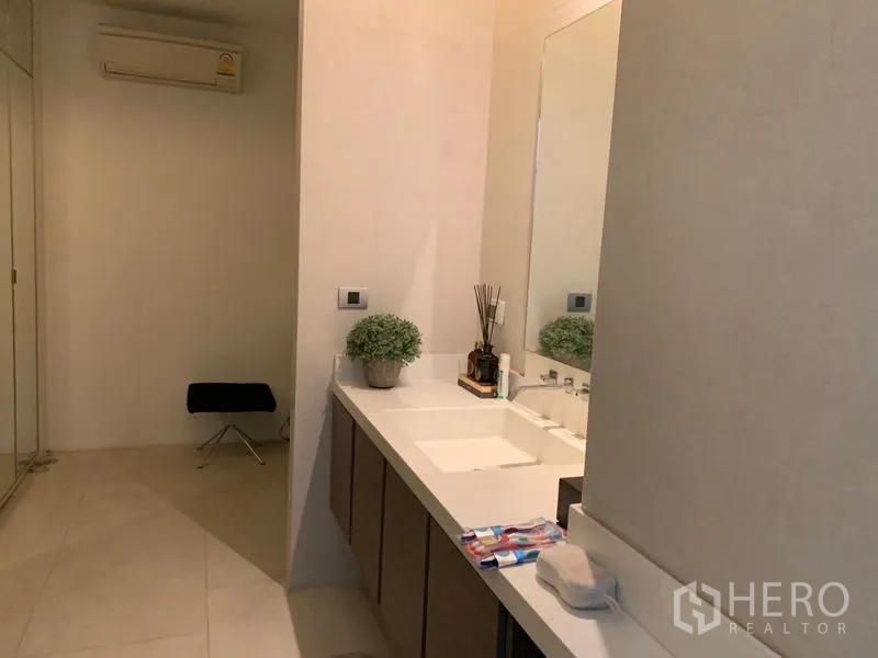 Townhouse for sale in Watthana, Bangkok - Contemporary bathroom with long vanity, large mirror and light tile flooring.