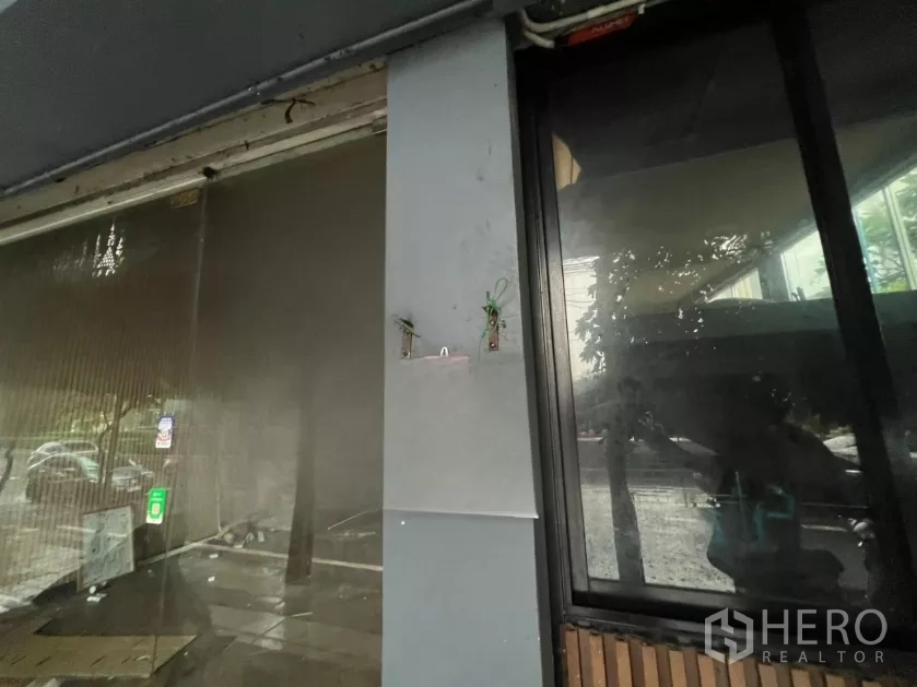 อาคารพาณิชย์ ให้เช่าในKhlong Toei, Bangkok - ภาพระยะใกล้ของกระจกหน้าร้านและเสากรุกล่อง มีจุดยึดป้ายและเงาสะท้อนบรรยากาศริมถนน