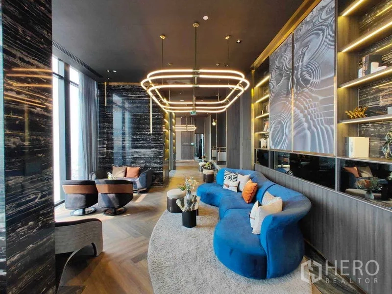 คอนโด ให้เช่าในWatthana, Bangkok - เลานจ์สไตล์โมเดิร์นพร้อมโซฟาสีน้ำเงินโค้ง ชั้นวาง และไฟตกแต่ง