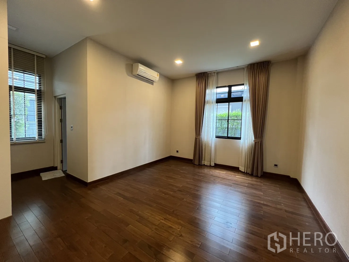 Detached House for rent or sale in Prawet, Bangkok - Large bedroom with wood flooring, corner windows and ensuite door.