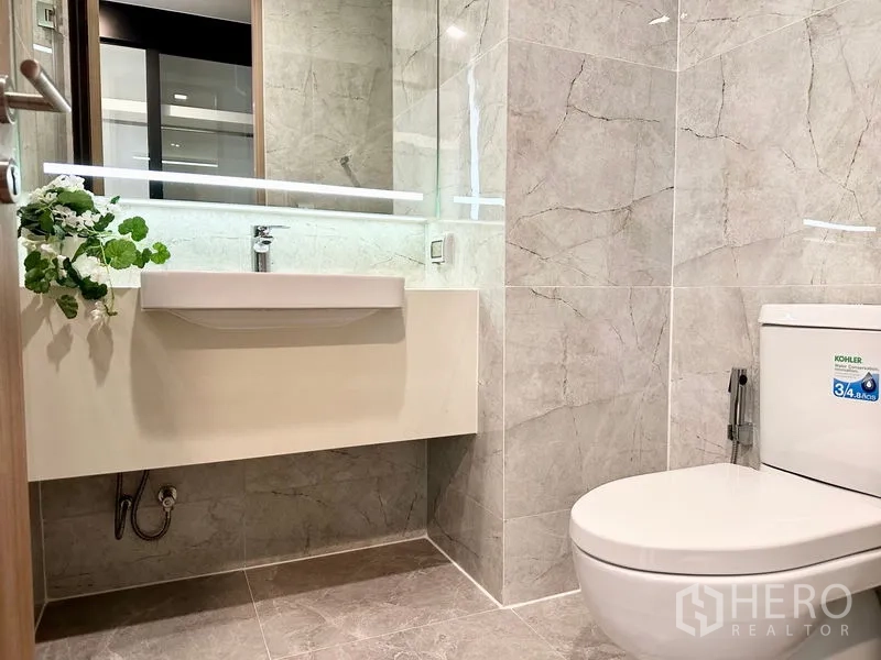 公寓 出租在Watthana, Bangkok - 现代浴室，带背光大镜、台盆与坐便，石材质感。