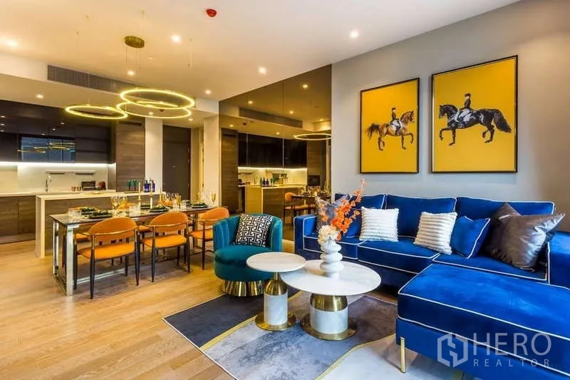 Condominium for rent in Pathum Wan, Bangkok - Living room with velvet sofa, nested coffee tables and modern artwork.