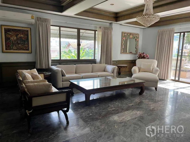 ทาวน์เฮาส์ ให้เช่าในKhlong Toei, Bangkok - ห้องนั่งเล่นพื้นหินอ่อน โคมระย้า และชุดโซฟา เปิดสู่ระเบียง