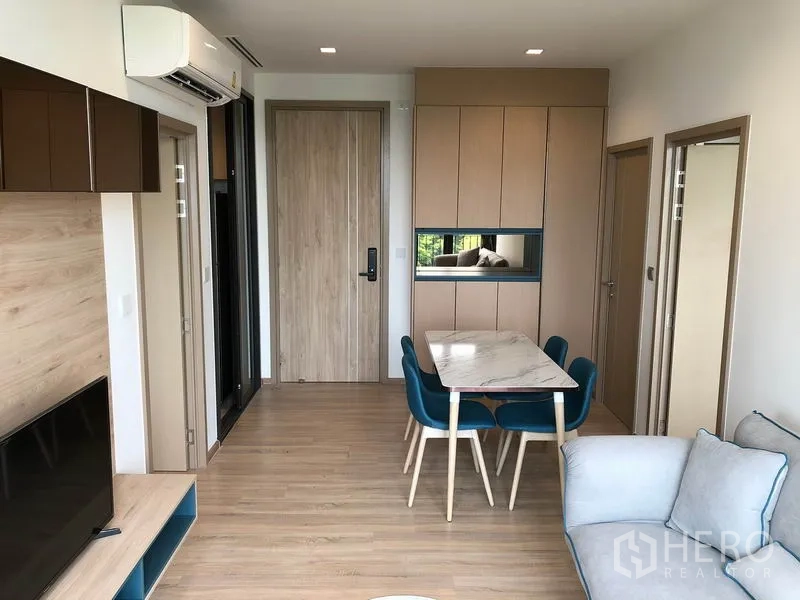 คอนโด ให้เช่าในWatthana, Bangkok - มุมทานอาหารโต๊ะหินอ่อน เก้าอี้สีฟ้า ตู้บิวท์อิน และประตูทางเข้า พื้นไม้โทนอุ่น