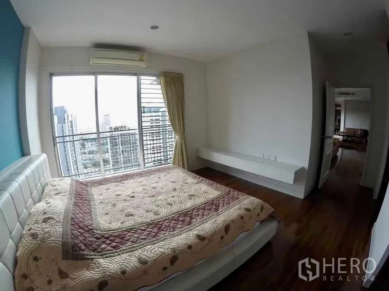 Condominium for rent or sale in Khlong San, Bangkok - Bedroom with floor-to-ceiling windows opening to a balcony with city views.
