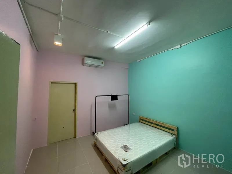 店屋 出租在Ratchathewi, Bangkok - 带空调的卧室或员工房，粉彩墙面与木质床架。