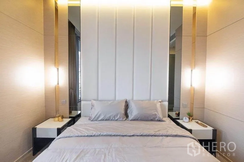 Condominium for rent in Watthana, Bangkok - Bed with tall upholstered headboard, matching bedside tables and soft ambient lighting.