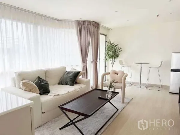 公寓 出售在Watthana, Bangkok - 开放式客厅，沙发、茶几、吧台椅与转角窗采光。