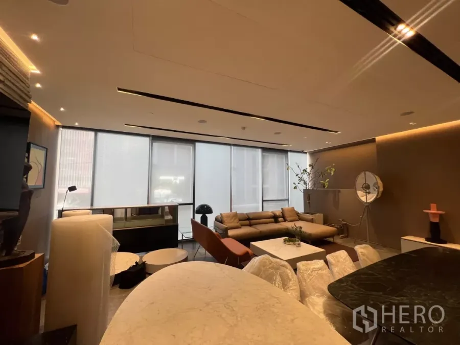 พื้นที่ขายปลีก ให้เช่า - พื้นที่ค้าปลีกแบบเปิดโล่ง กระจกสูงจรดเพดาน ไฟดาวน์ไลท์ และโซฟานั่งรับรองข้างเคาน์เตอร์หิน.