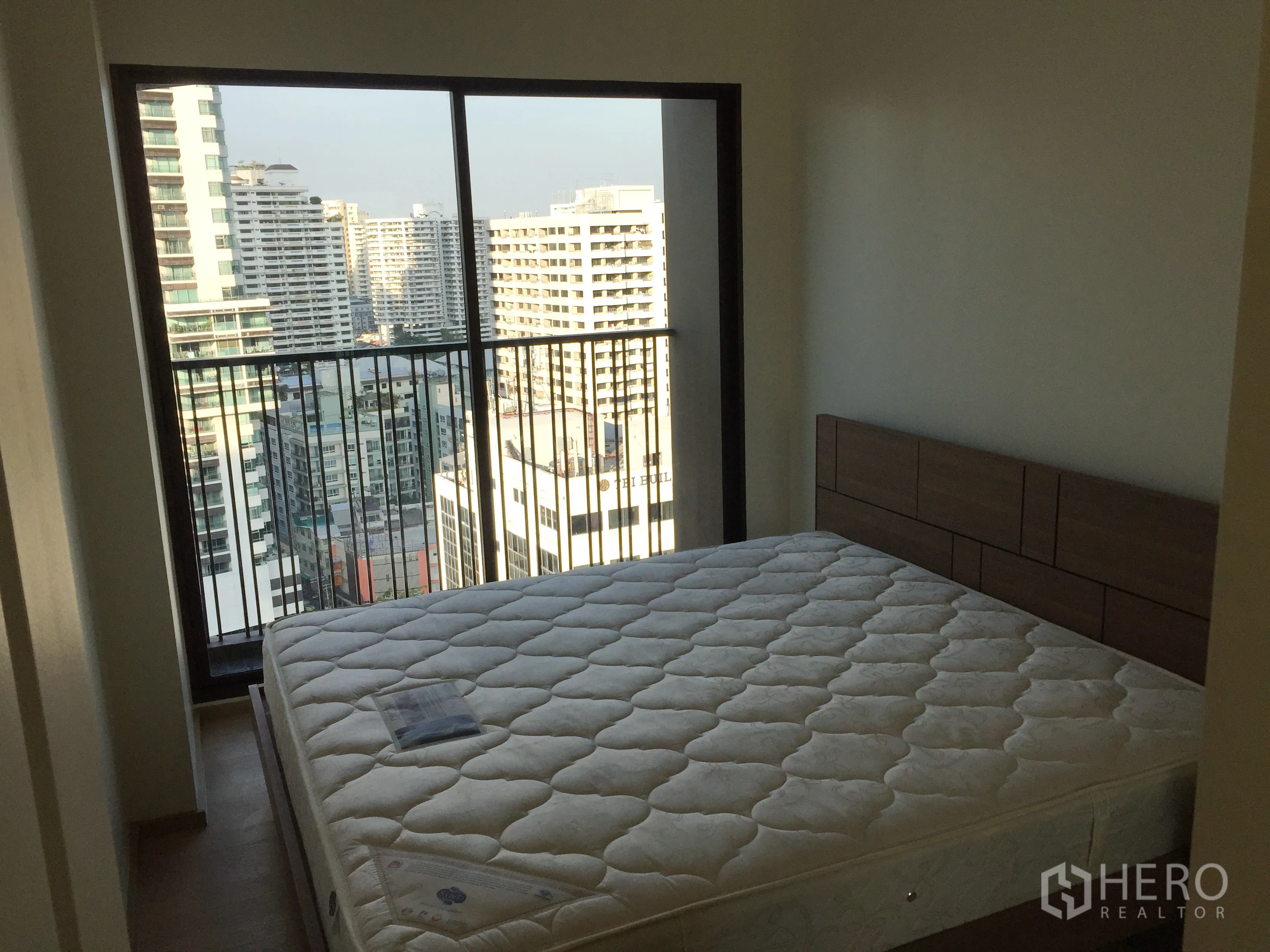 คอนโด ให้เช่าในBangkok - ห้องนอนพร้อมหน้าต่างบานใหญ่และราวระเบียง มองเห็นวิวตึกสูงของเมือง