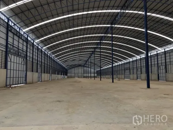 Factory for rent or sale in Lat Lum Kaeo, Pathum Thani - Expansive warehouse interior with arched steel trusses and daylight strips along the roof.