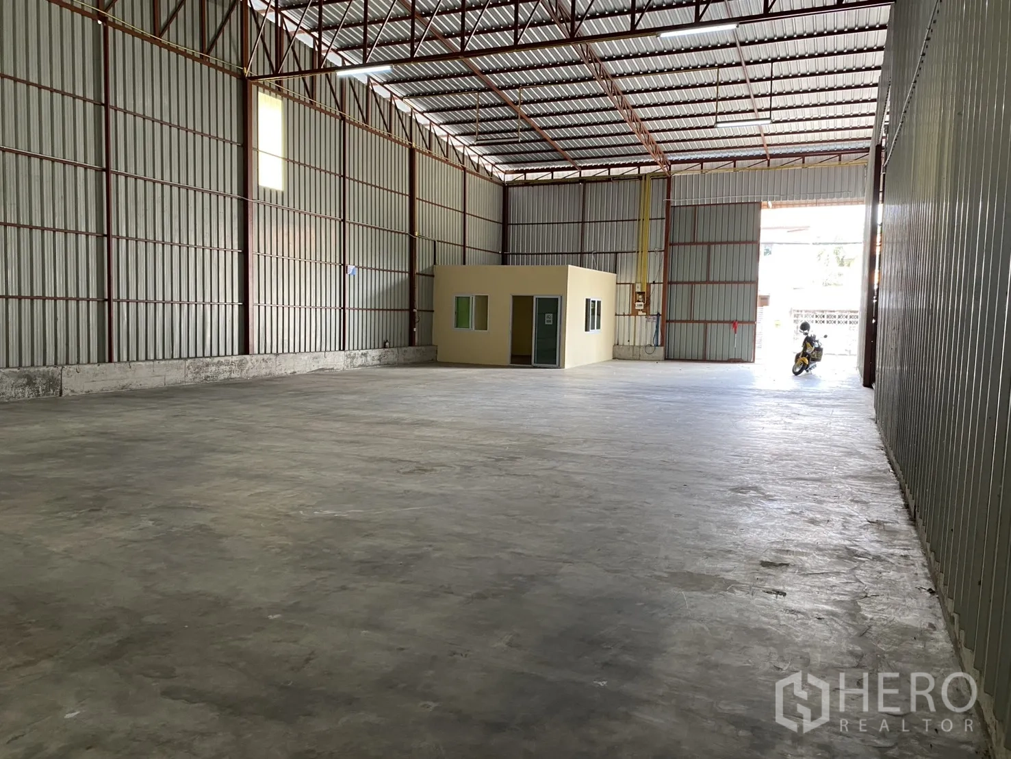 Warehouse for rent in Bueng Kum, Bangkok - Open warehouse space with internal office room and a large sliding entry door.