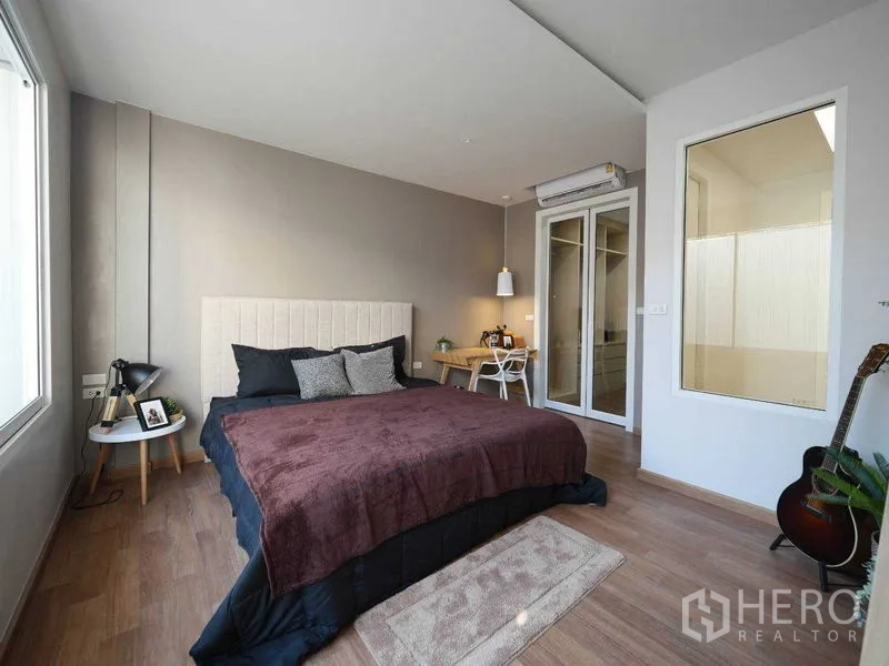 ทาวน์เฮาส์ ให้เช่าในWatthana, Bangkok - ห้องนอนใหญ่สว่าง พื้นไม้ หน้าต่างบานกว้าง โต๊ะทำงาน และประตูกระจก