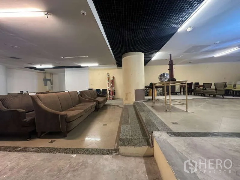 零售空间 出租 - 室内高低落差台阶，中央立柱、瓷砖地面与座位区