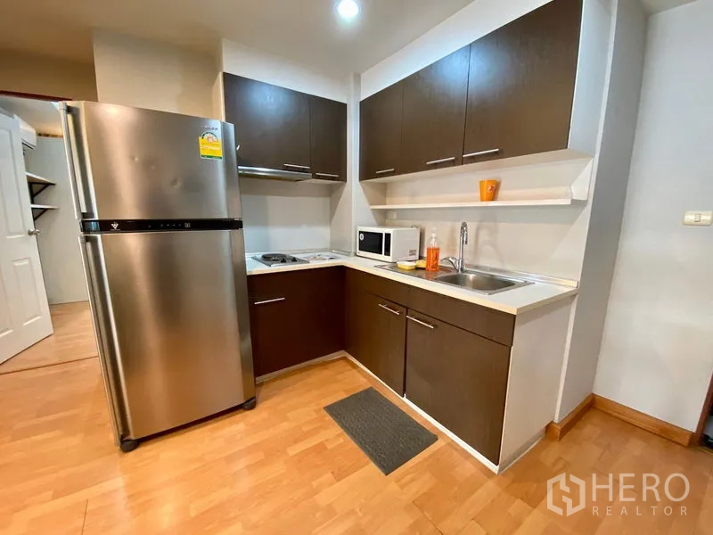 คอนโด ขายในKhlong Toei, Bangkok - ครัวรูปตัวแอลพร้อมตู้เย็นสแตนเลส ไมโครเวฟ ตู้เก็บของครบ และพื้นไม้