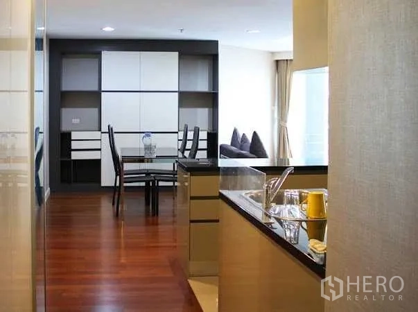 Condominium for rent in Huai Khwang, Bangkok - View from the kitchen sink to the dining area with built-in shelving and hardwood flooring.
