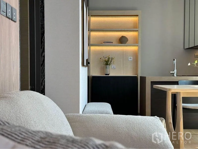 公寓 出租在Pathum Wan, Bangkok - 内置层架带暖色灯带，邻近沙发与餐桌。