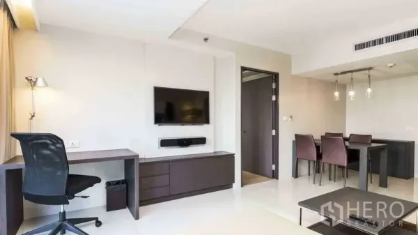 Apartment for rent in Watthana, Bangkok - Open-plan lounge with wall-mounted TV, built-in desk and dining area with pendant lights.