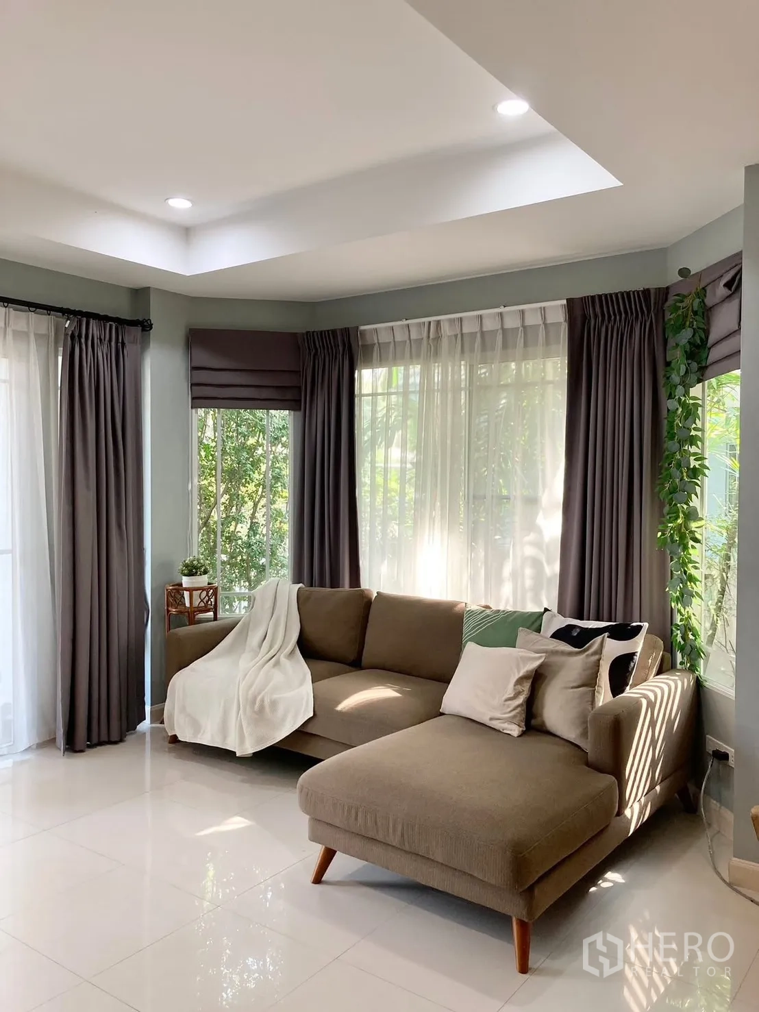 独栋房屋 for rent in Prawet, Bangkok - 客厅转角大窗，L形沙发与双层窗帘。