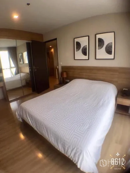 Condominium for rent in Sathon, Bangkok - Cozy bedroom with double bed, wood headboard, mirrored wardrobe and warm wood flooring.